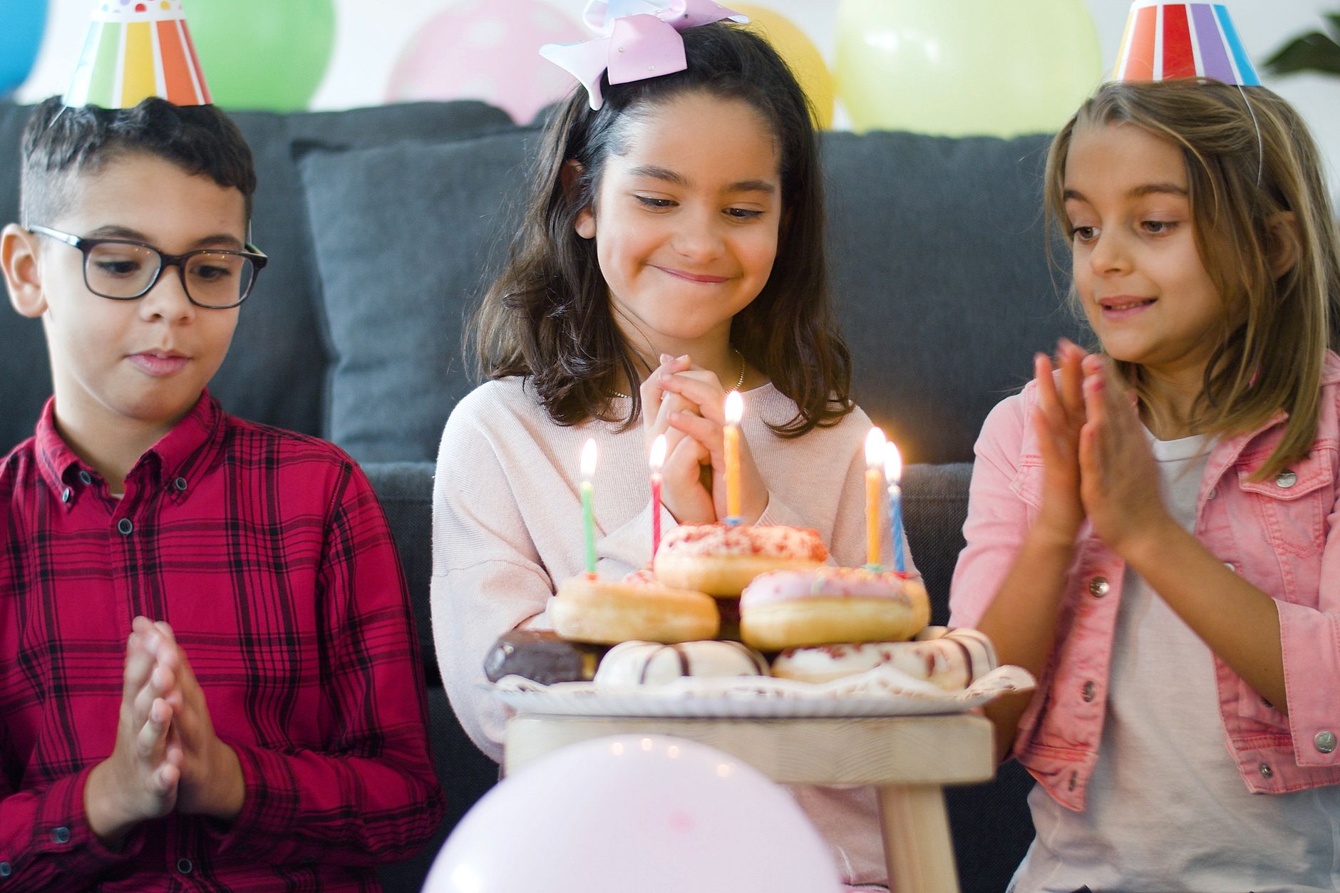 A joyful birthday celebration with children and sparkling candles on donuts.
