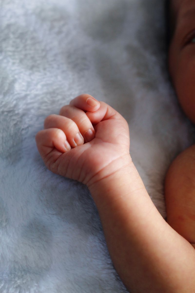 Tender close-up of a newborn baby's hand resting on a cozy blanket.