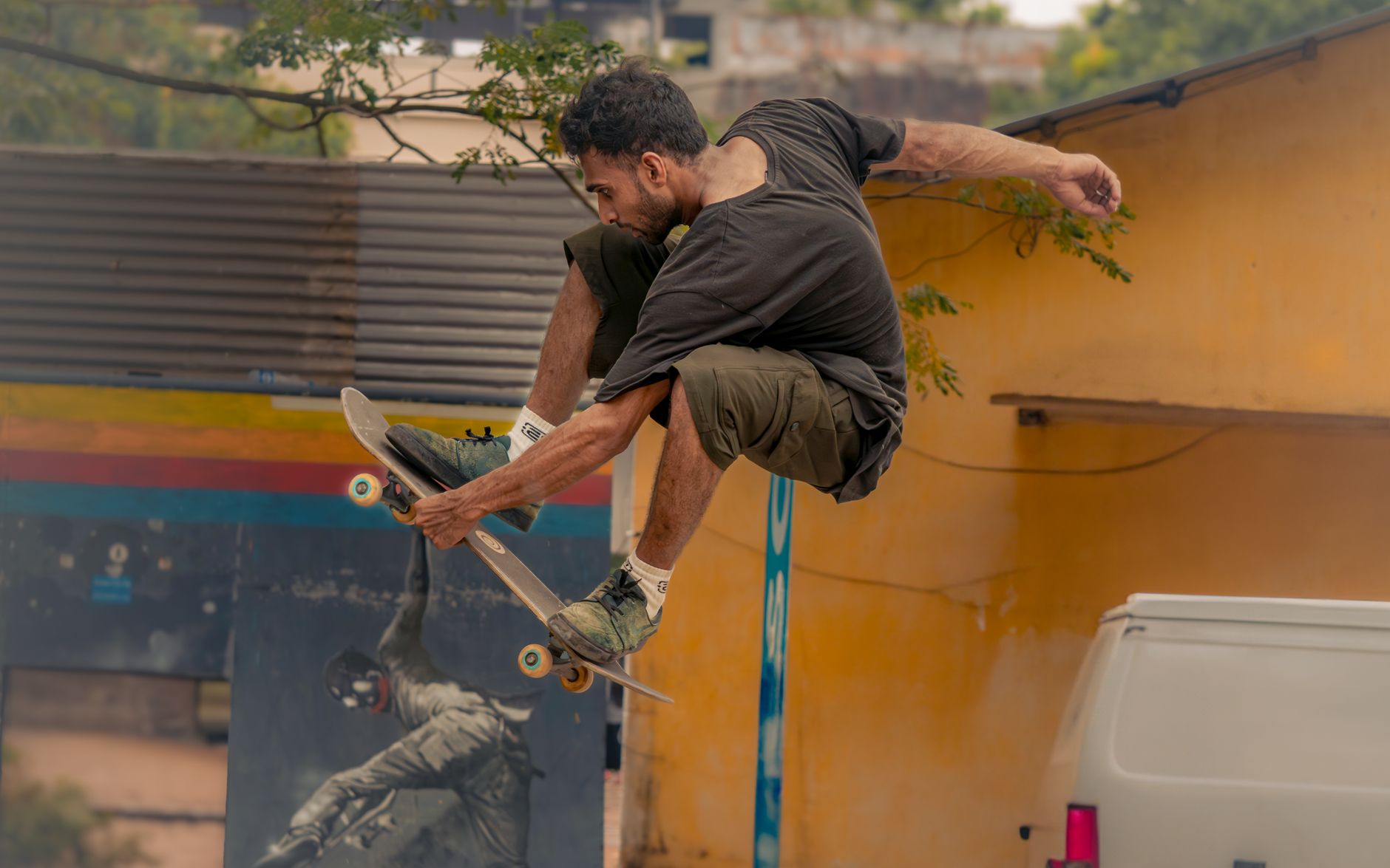Skateboarder performing a high jump trick in a colorful urban environment.