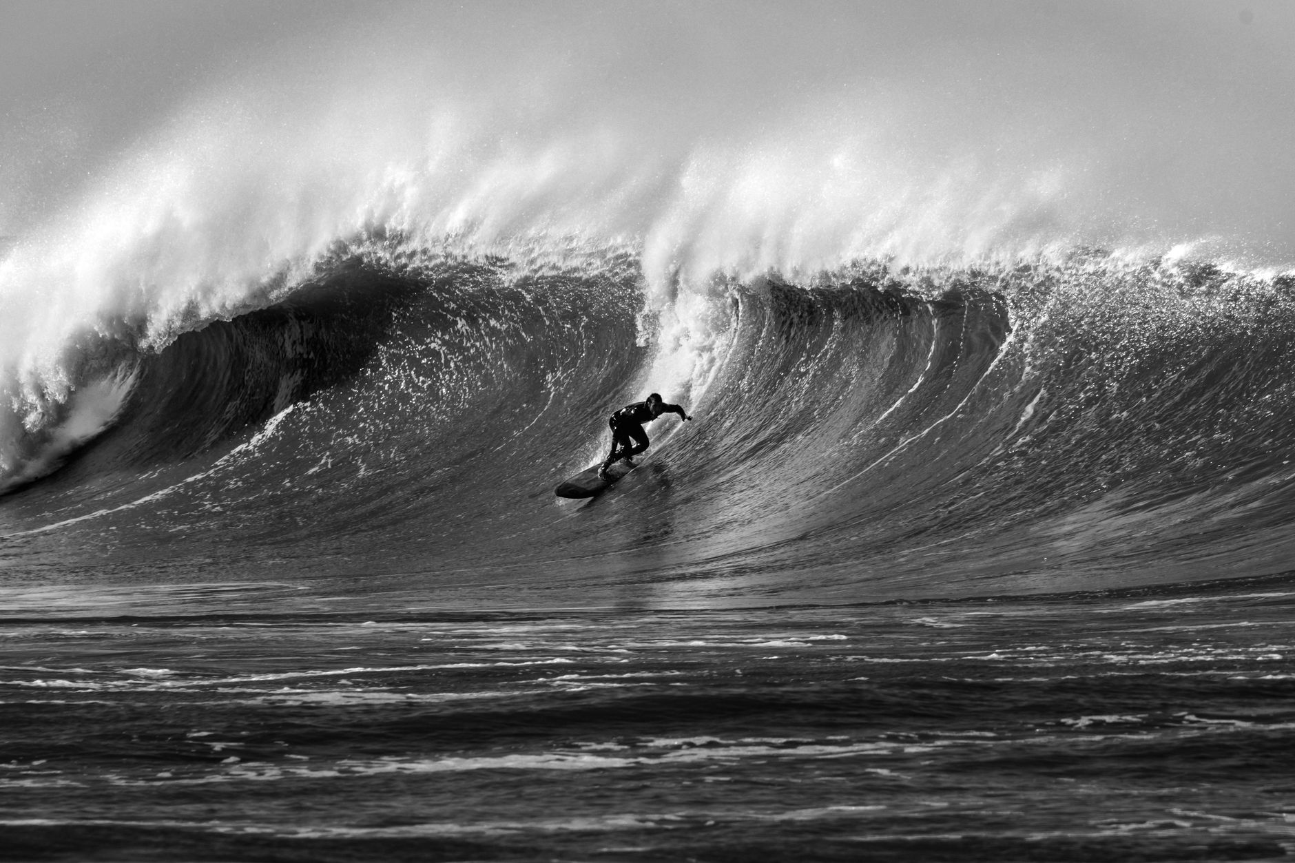 A stunning black and white photograph capturing a surfer skillfully navigating a massive wave.